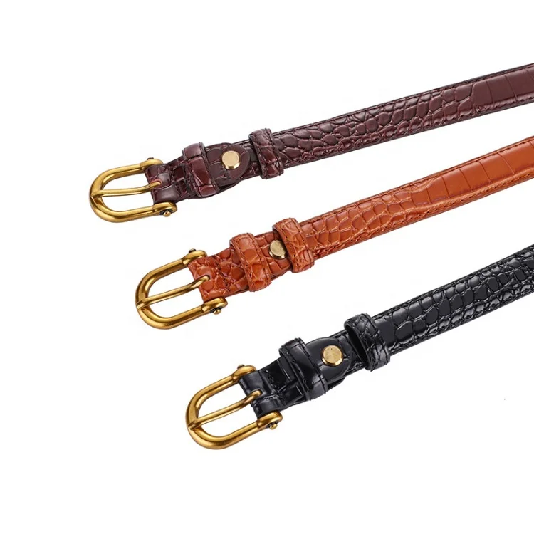Three crocodile-patterned belts in brown, orange, and black with gold buckles on a white background.
